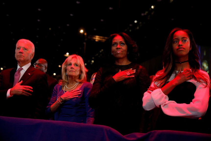 LtoR: Joe Biden, his wife Jill Biden, Michelle Obama and her daughter Malia stand for the national anthem.