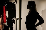 Silhouette of a woman standing in a semi-darkened room