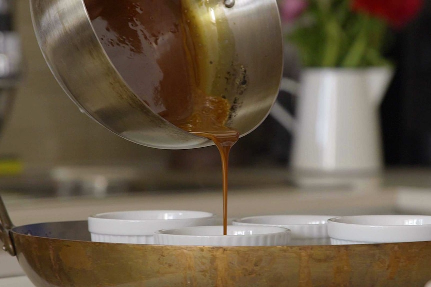 Saucepan full of caramel is poured into ramekins.