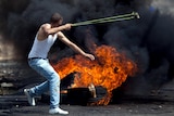 A Palestinian demonstrator throws a stone toward Israeli soldiers during clashes in the West Bank.