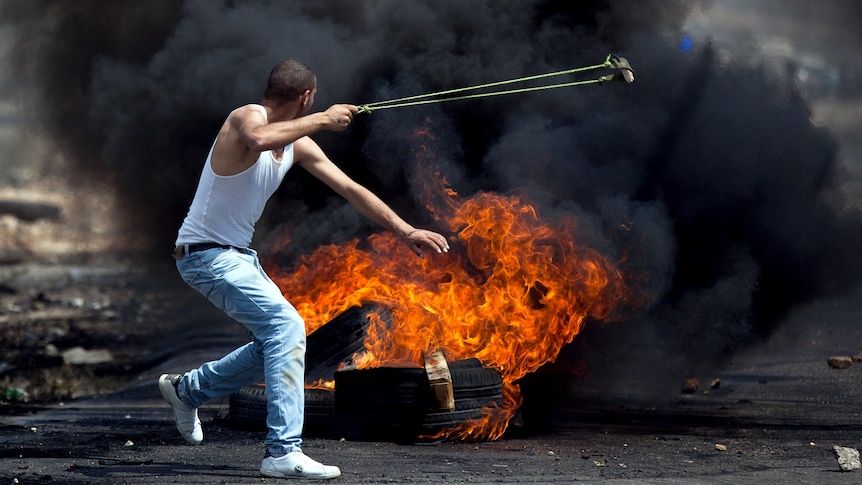 A Palestinian demonstrator throws a stone toward Israeli soldiers during clashes in the West Bank.