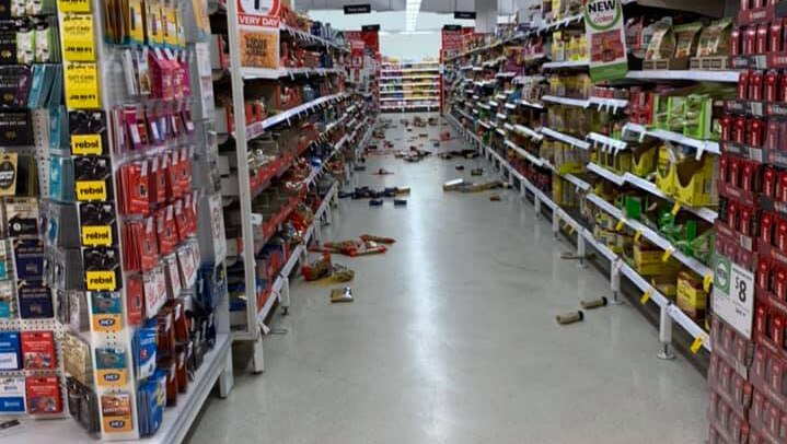 Supermarket aisle with groceries strewn on the floor.