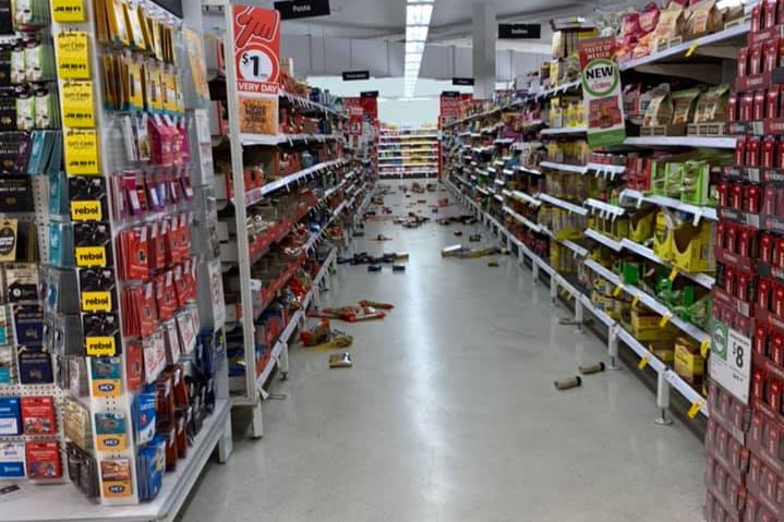 Supermarket aisle with groceries strewn on the floor.