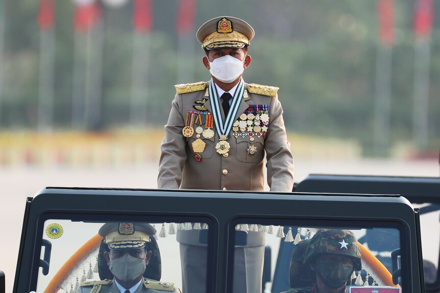 Masked military man standing in a car.