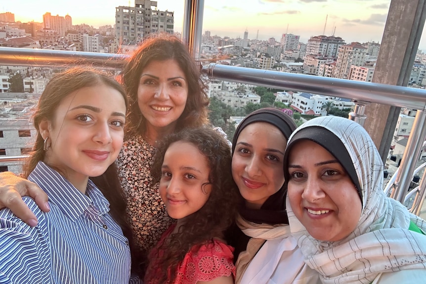 Samah Sawabi with four female family members in Gaza with railing and buildings in city behind