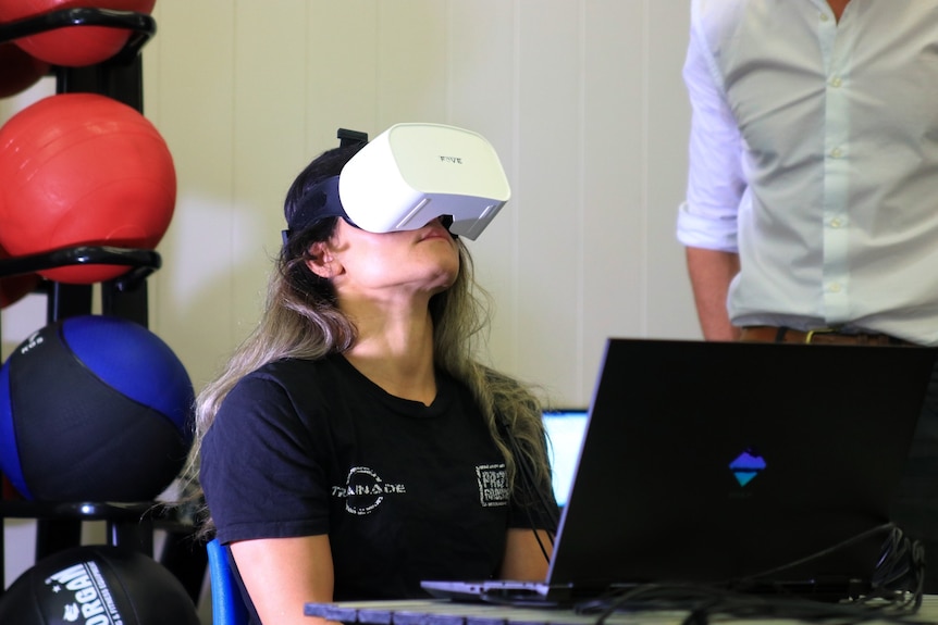 A dark-haired woman with a VR headset looking up.