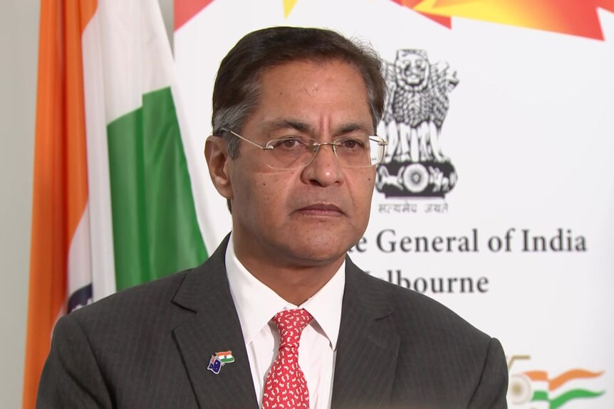 A man in a suit in front of an Indian flag