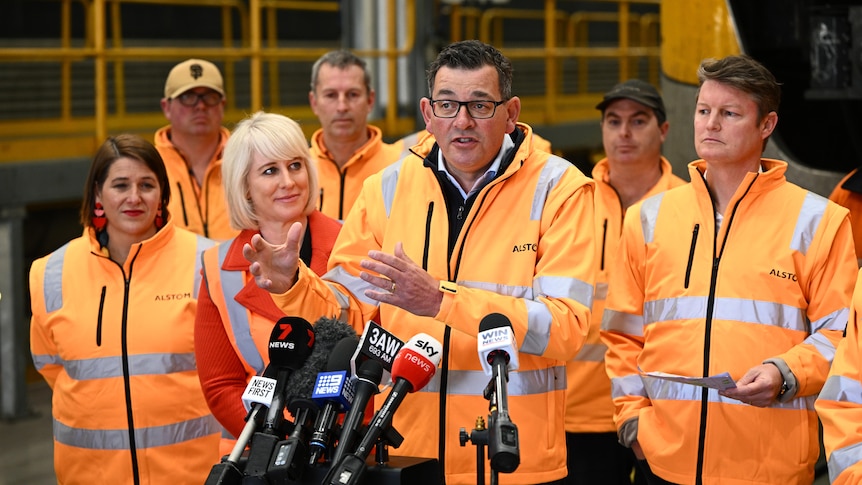 Daniel Andrews, flanked by people in high-vis including his wife and minister Ben Carroll.