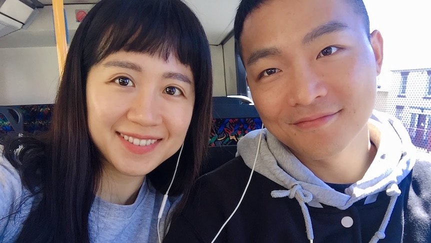 A young Korean male and female smiling on a train.