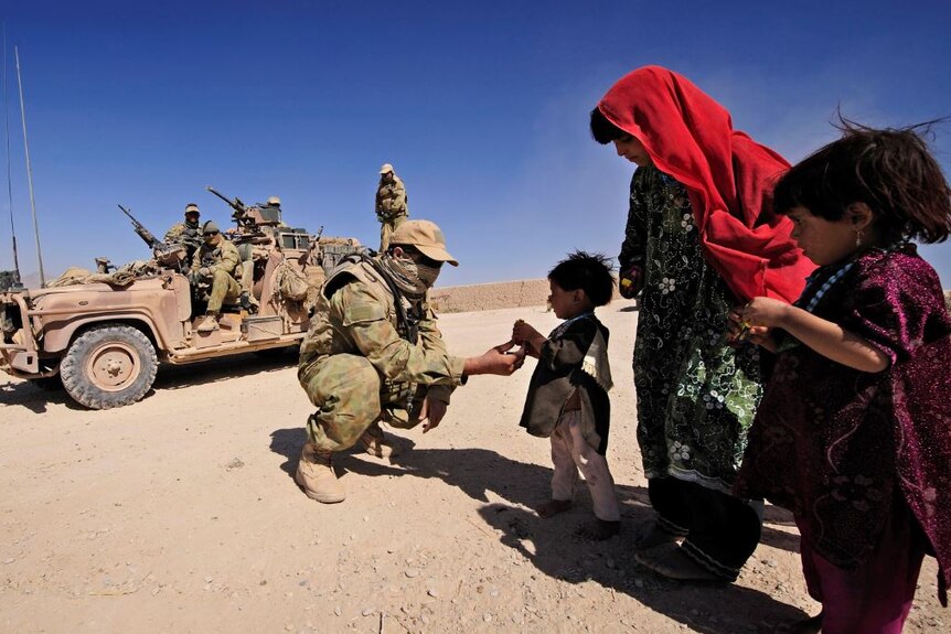 A special forces soldier gives sweets to Afghan children.