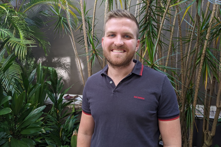 Eliot Hastie stands in front of a courtyard garden in his apartment complex.