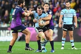 Cronulla's Paul Gallen (C) is tackled by Melbourne's Kenny Bromwich and Cooper Cronk at AAMI Park.