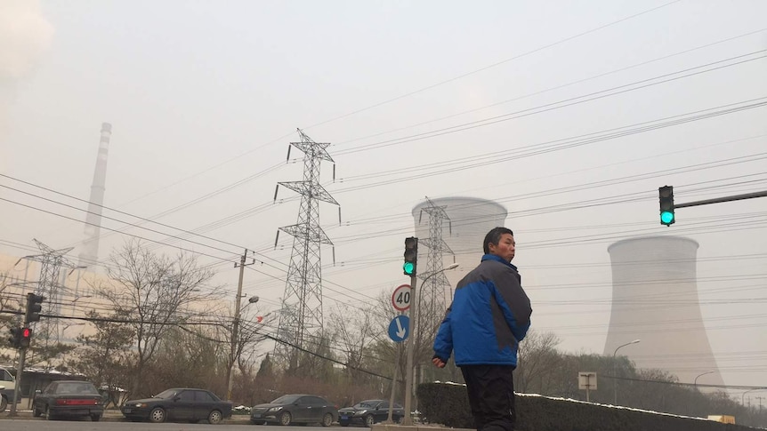 A man walks past a power plant in eastern Beijing.