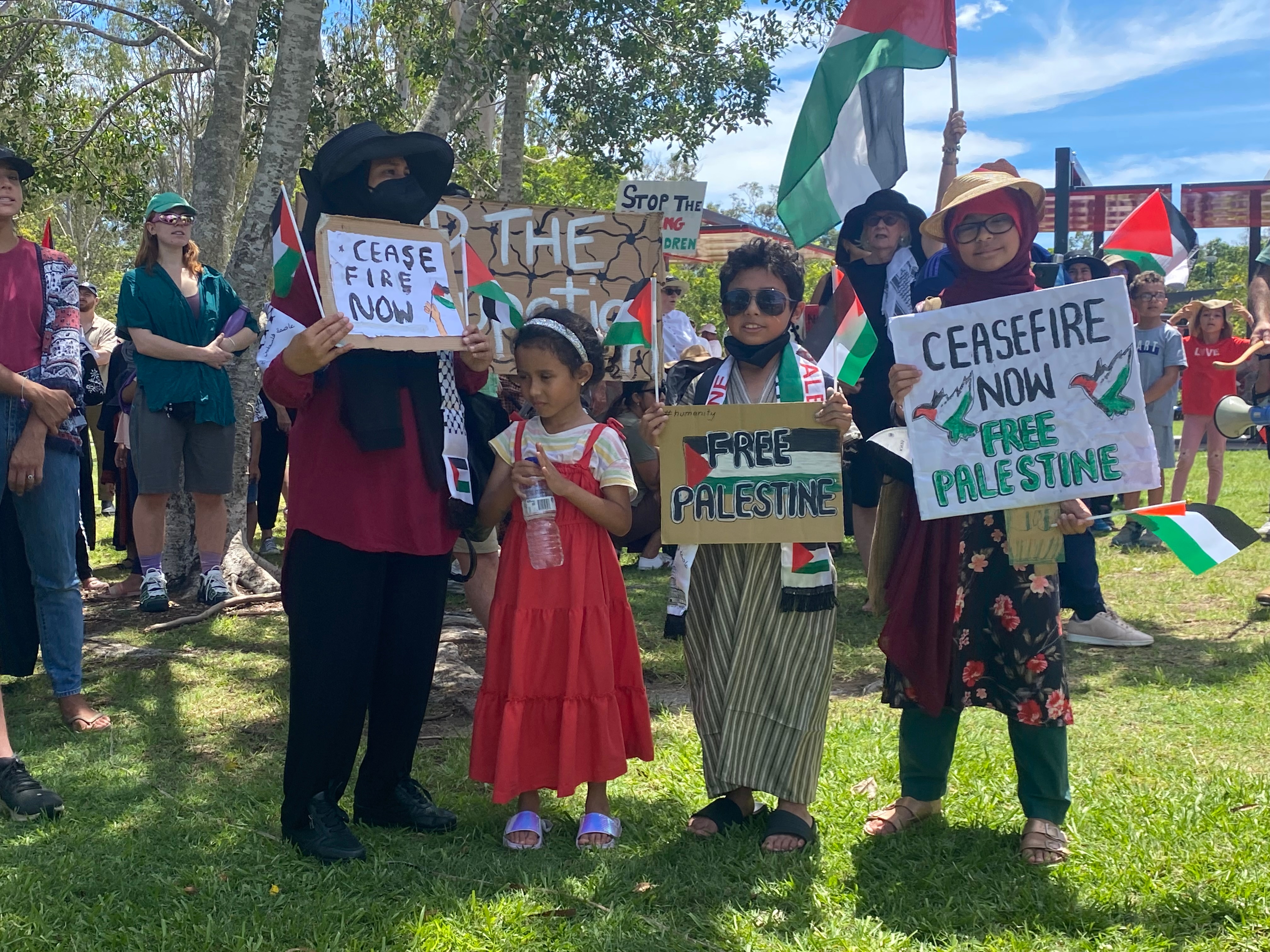 a family holds pro-palestinian placards at logan gardens in brisbane 