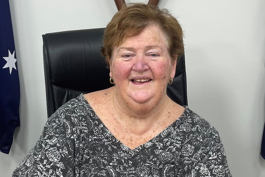 A woman with short, brown hair, sitting in an office chair.