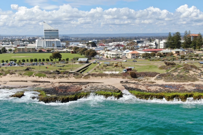 A drone shot over a beach looking back at a coastal town