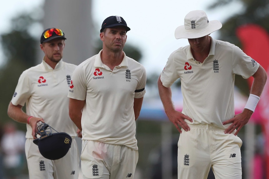Joe Root, James Anderson, and Stuart Broad look dejected as they leave the field.