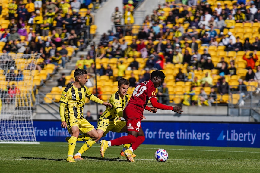 Adelaide United's Musa Toure takes on two players in a clash against the Wellington Phoenix.