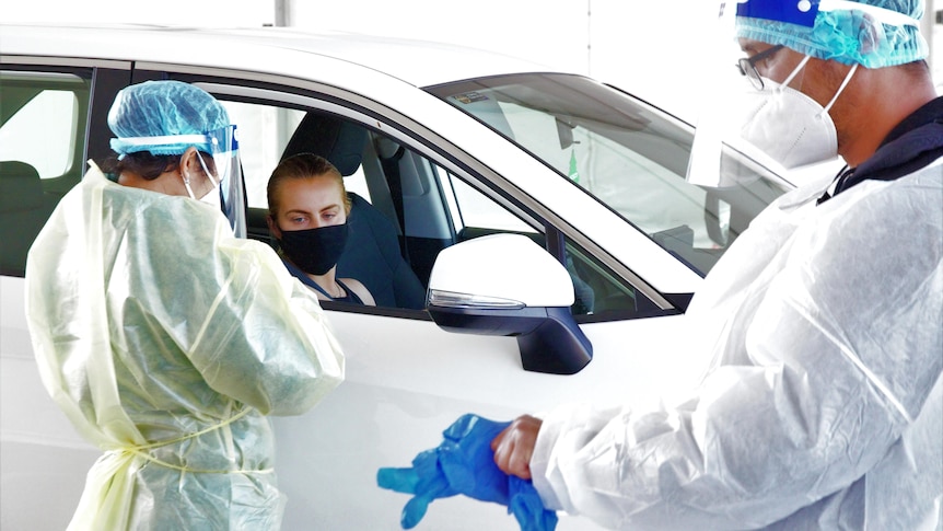 A lady in a mask lines up at testing clinic.