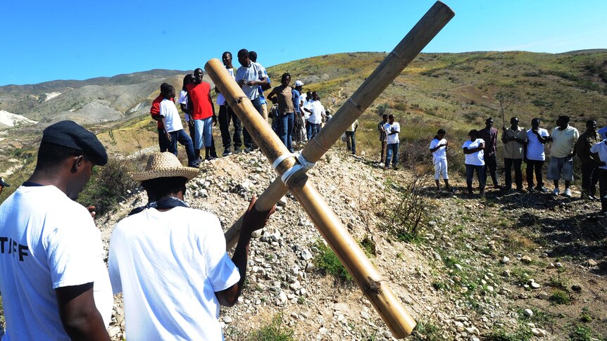 Haitians carry a cross up a hill at Titanyin on the 2nd anniversary of the 2010 earthquake.