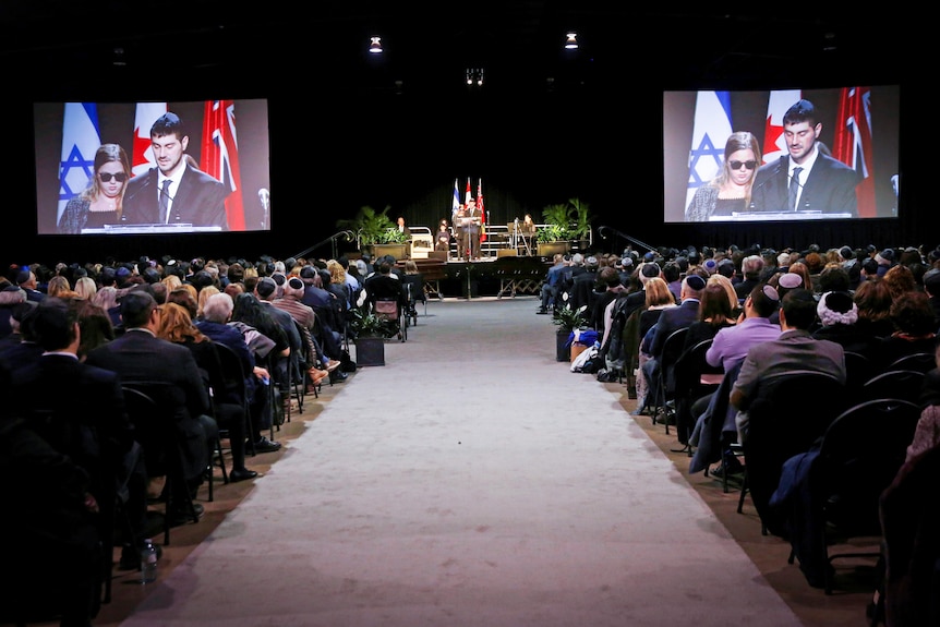 A room filled with people sitting before two coffins 