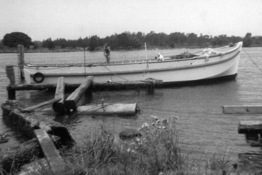 An old wooden fishing trawler in a river, partly built.