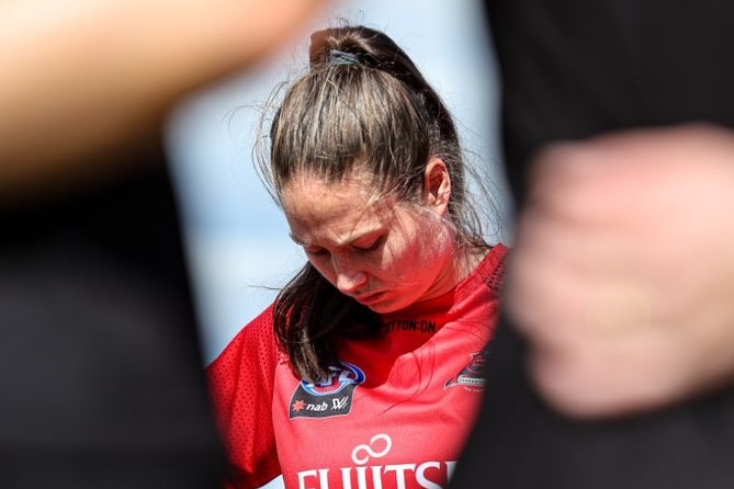 A close-up image of Danielle Marshall with her head bowed in a team huddle.