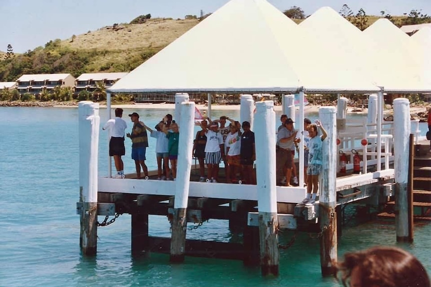 A group of people stand looking out on a jetty. 