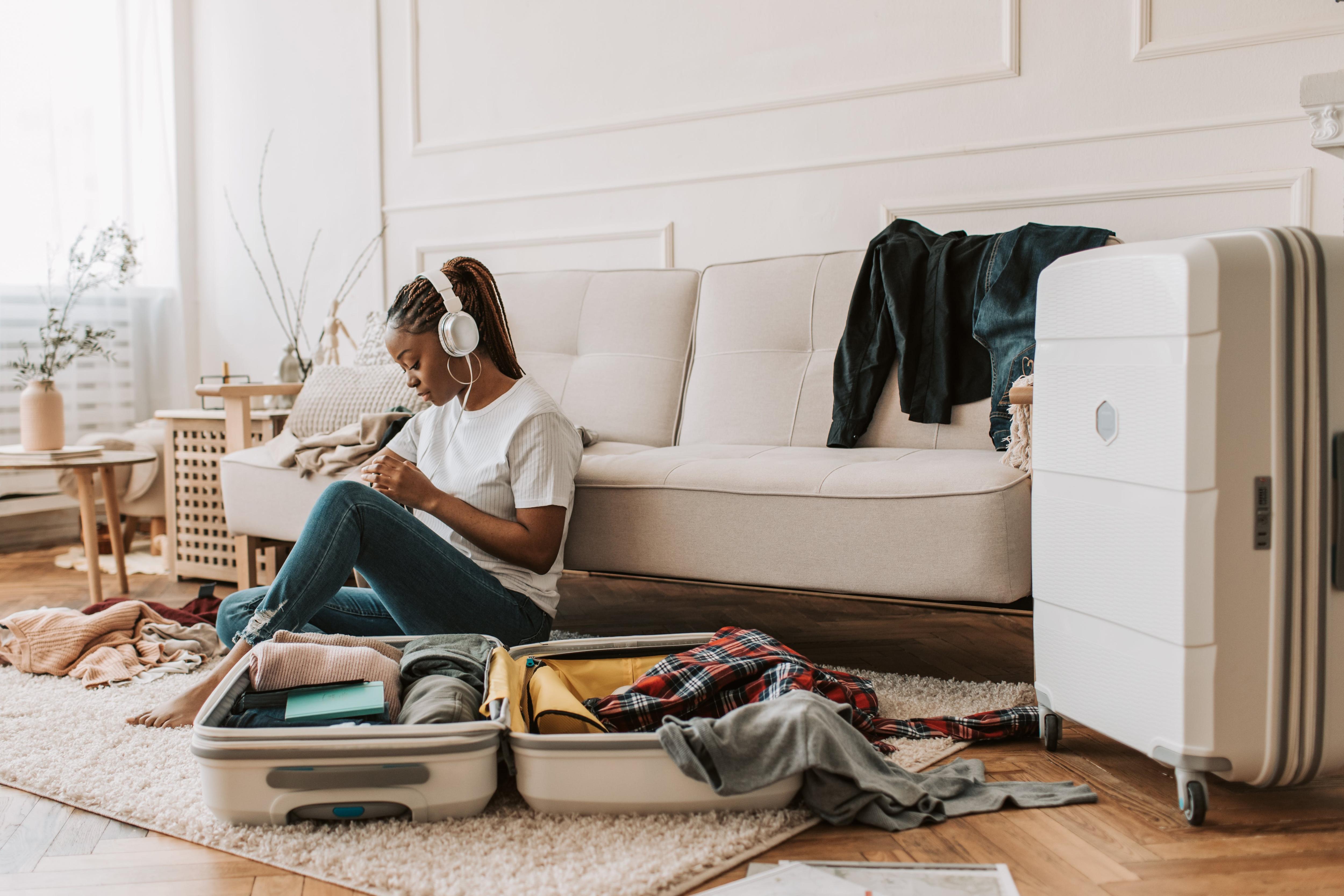 A woman sits in an apartment with an open suitcase.