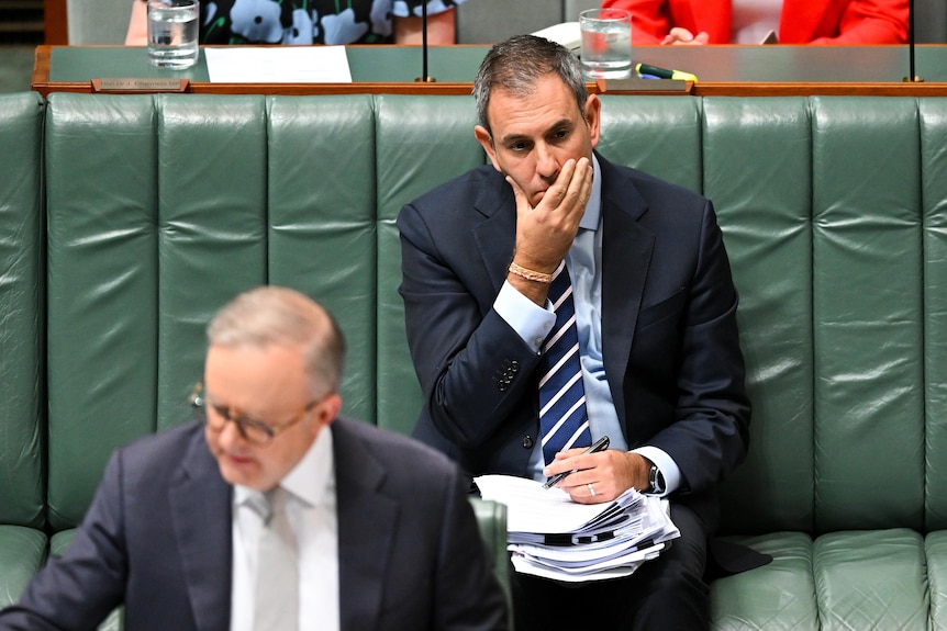 A middle-aged man in a suit with grey hair sits on the green chairs of Australia's parliamentary frontbench.