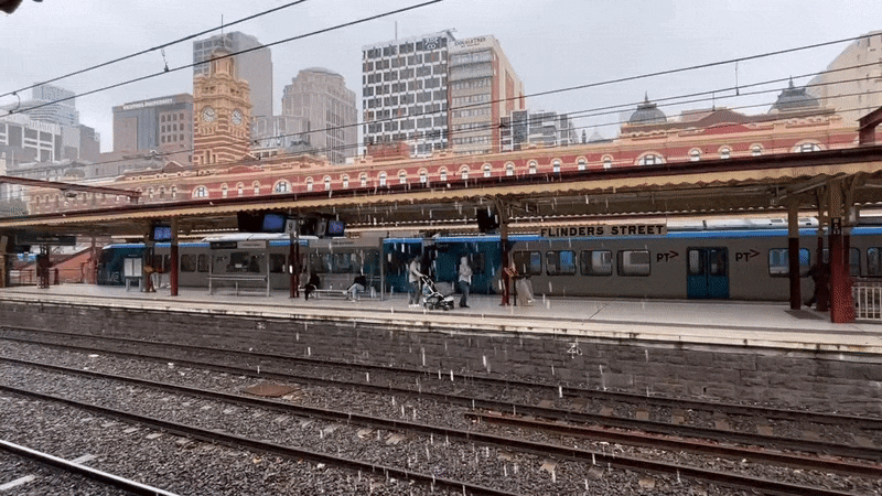 GIF of rain falling over a train track at Flinders St Station.