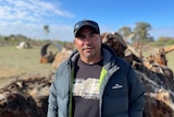 A man stands in front of a tree root ball.