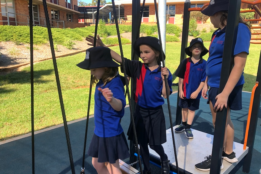 Students on play equipment at a school.