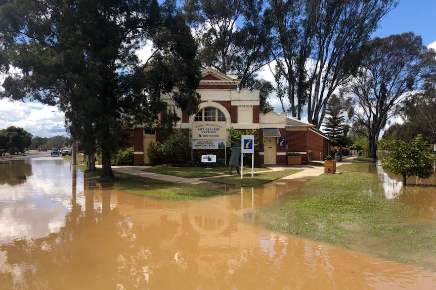 A grand old building in the country, surrounded by floodwater.