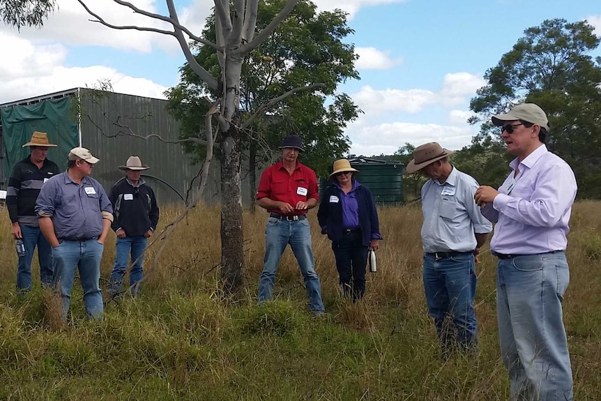 Jason Virtue stands in front of a crowd in a pasture