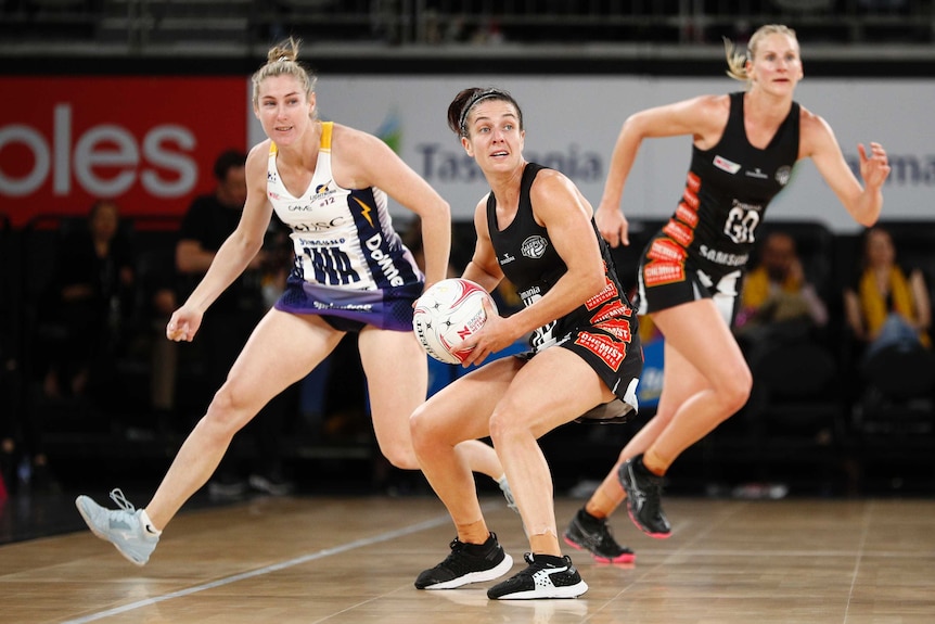 A netballer plants her feet and looks up-court as she gets ready to pass.