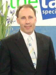 A man in a suit smiles at a camera