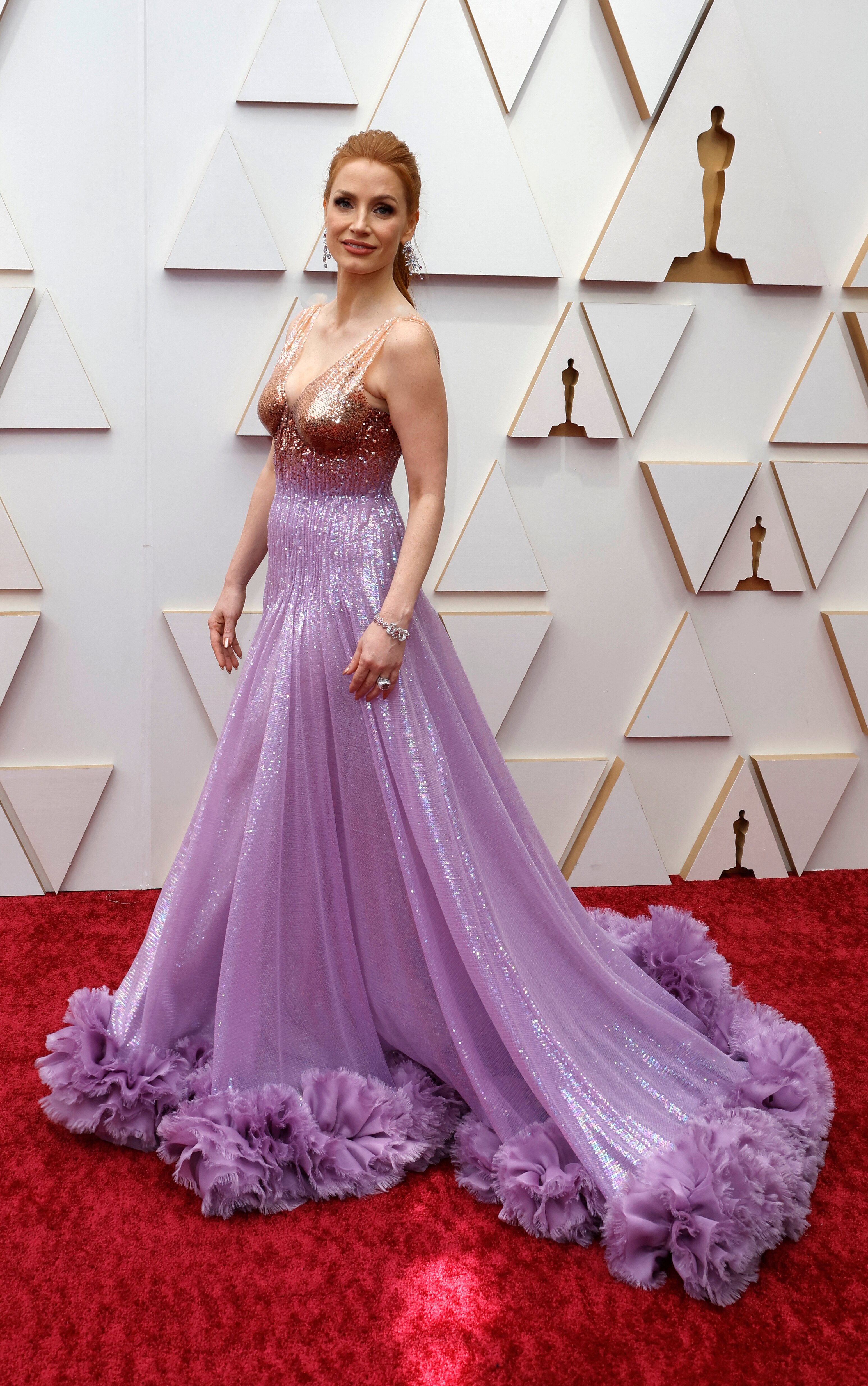 actor jessica chastain smiles on the oscars red carpet wearing a lilac ruffled gown with a sequined bodice 