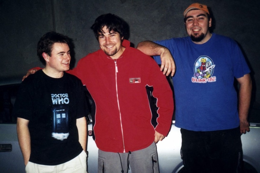 A male teenager in a Doctor Who T-shirt stands next to a male teen in a red jacket, and a third, wearing a blue Blink-182 
