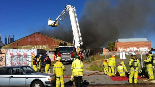Firefighters use a crane to get to a fire at a warehouse in West Perth