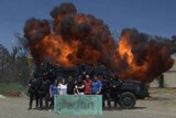 The family poses with officers in front of an explosion.