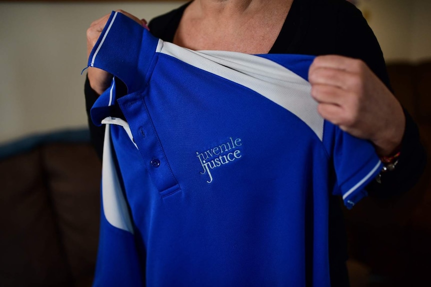 A woman holds up a uniform that says 'Juvenile Justice'.