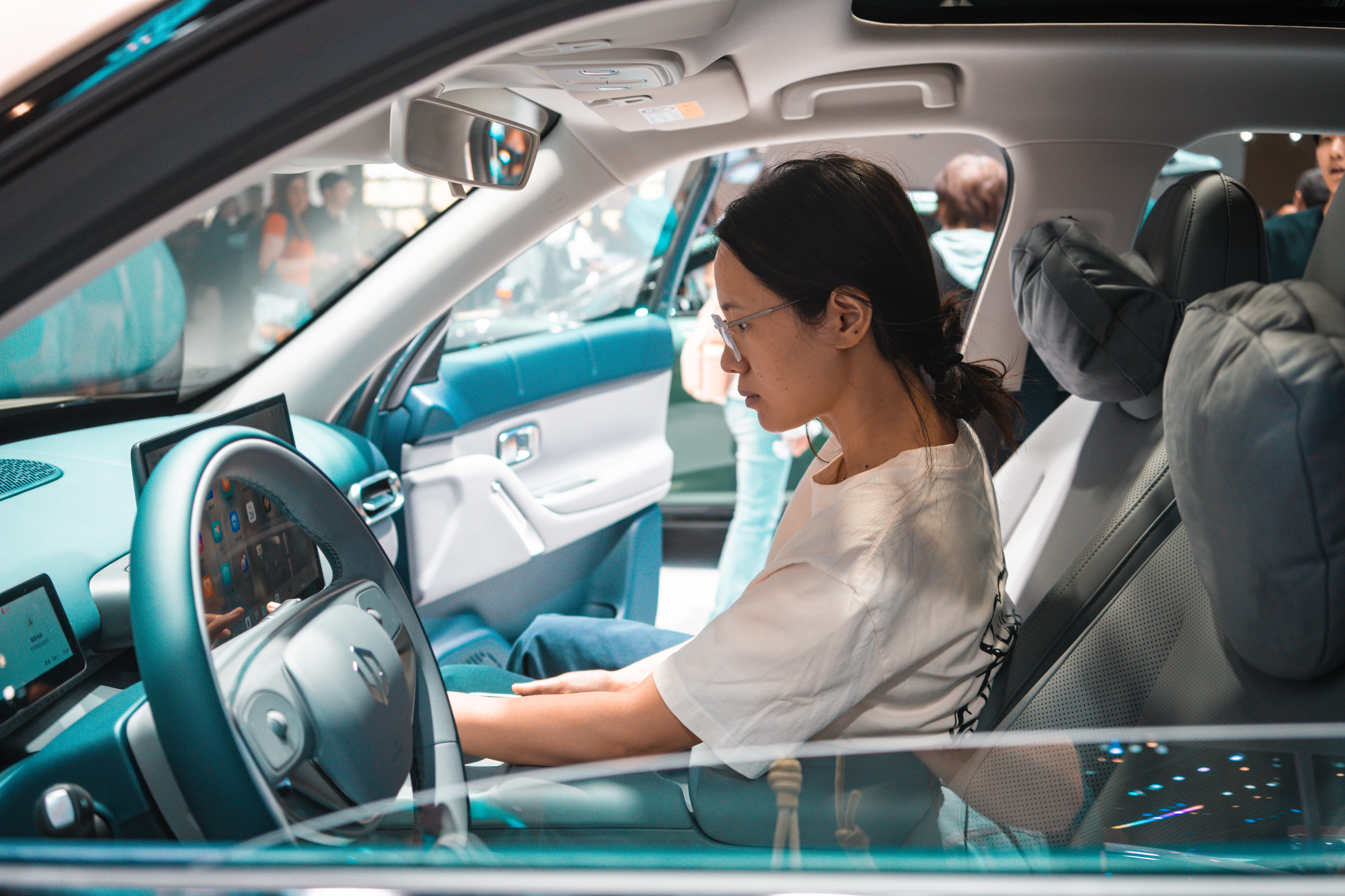 A woman sitting in the passenger seat of an electric vehicle at a car show in China.