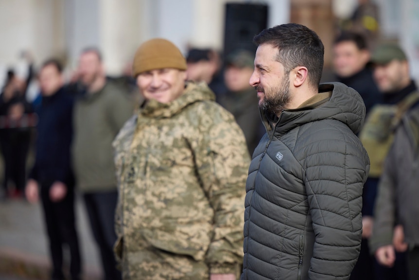 Un hombre se para con soldados en uniforme ucraniano.