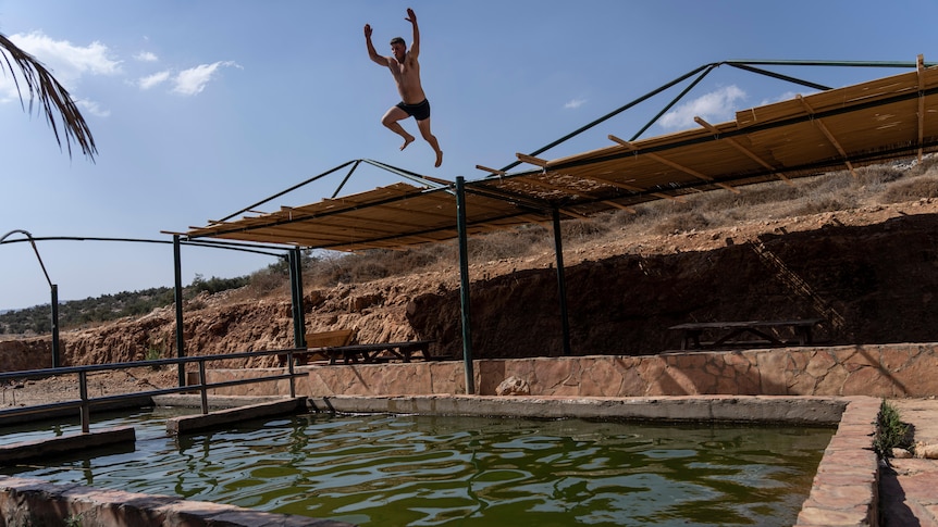 An off-duty Israeli soldier jumps into Kfir spring.