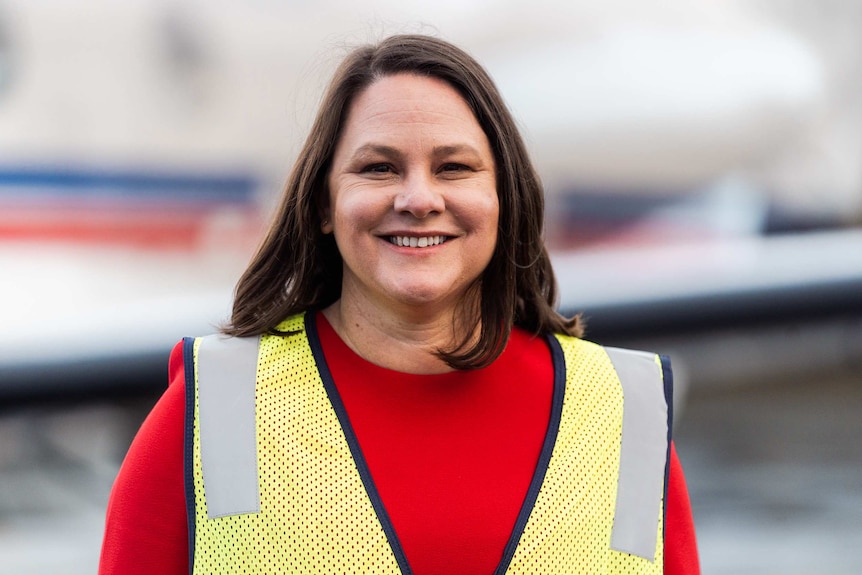 A head and shoulders shot of a smiling RFDS chief executive Rebecca Tomkinson wearing a red top and yellow hi-vis vest.