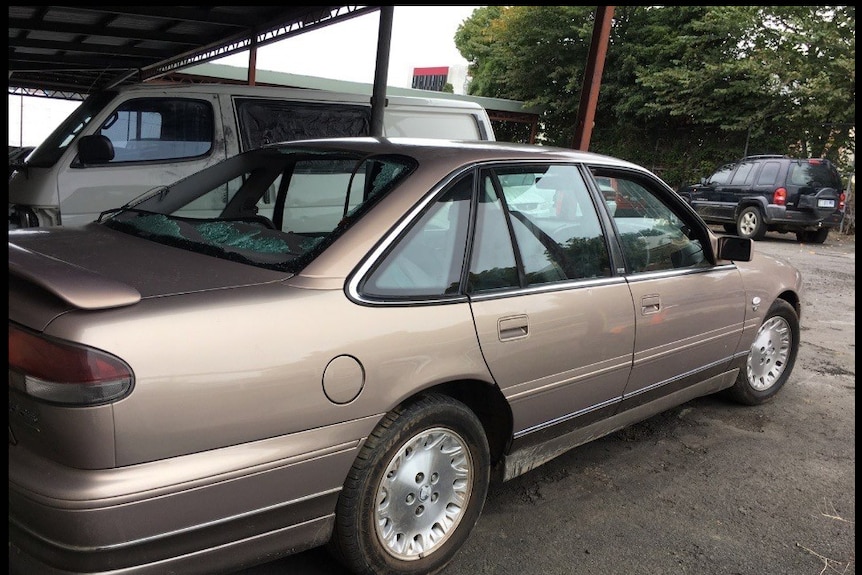 A gold coloured sedan with a smashed back window