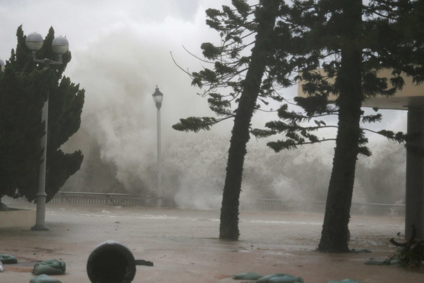 Waves and water crash into a concrete pedestrian area in Hong Kong.