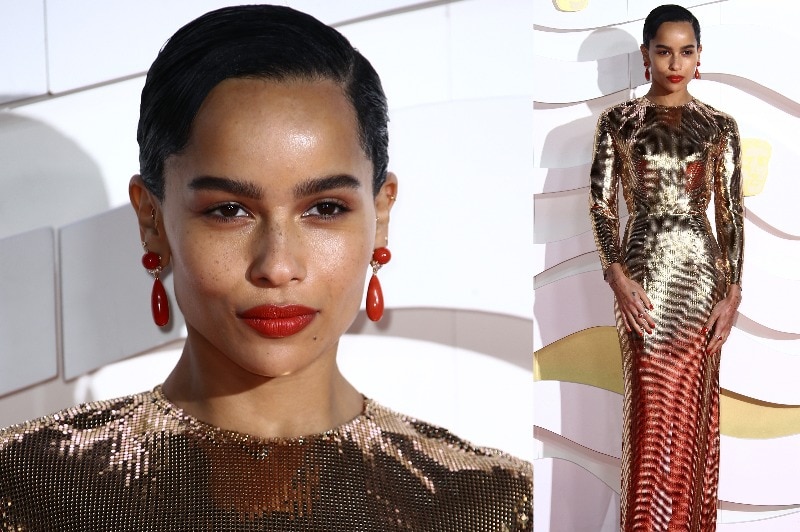 Zoe Kravitz wearing a long-sleeved gold sequined dress with red lipstick and red earrings.