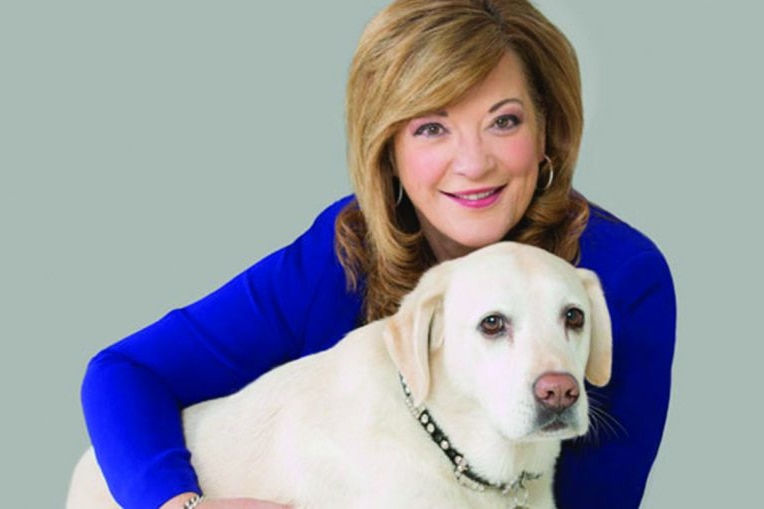 A woman in a blue top hugging a dog